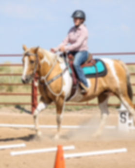 A woman rides her palomino paint in a Cowboy Dressage test