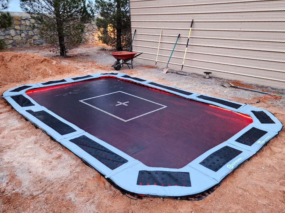 Rectangular in-ground trampoline, black mat, light blue padding and led lights