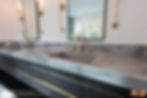 His and her's sink closeup showing the grey marble and gold handles.