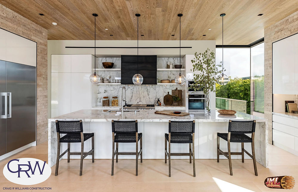 Marble kitchen island with bar chairs and wood ceilings.