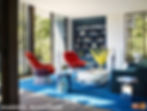 Post-modern and mid-century furniture in living space with floor to ceiling windows.