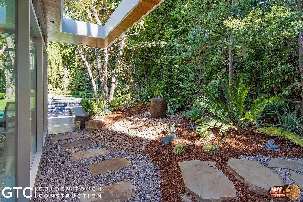 Backyard walkway highlighting the landscaping including greenery, stone paths, and gravel.