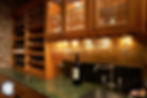 Wooden wine cellar with marbled countertops and wine glass hanging rack.