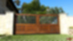 Grass patterned driveway leading up to a wood gate that has an iron grid halfway up. 
