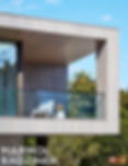 Contemporary home balcony with wood siding and glass panels.