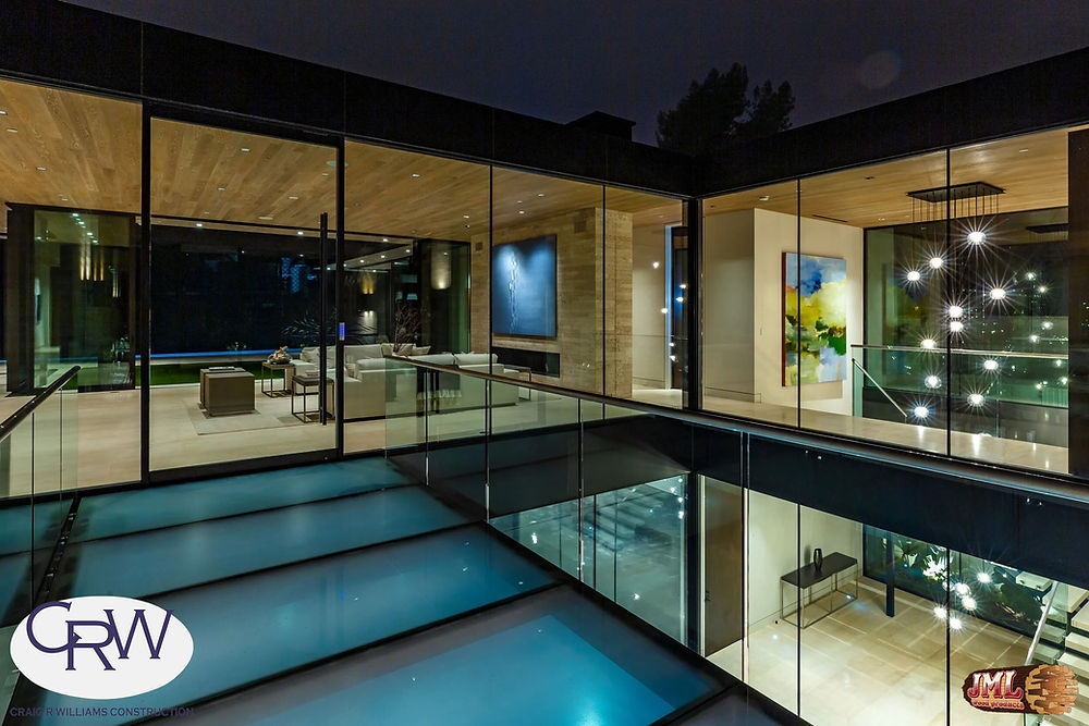 Glass bridge leading to upstairs living area, overlooking the bottom level at night.