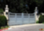Small muted blue driveway gate with two white column towers.
