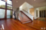Ground floor wooden staircase and entrance area that highlights the continuance use of hardwood flooring throughout the home.
