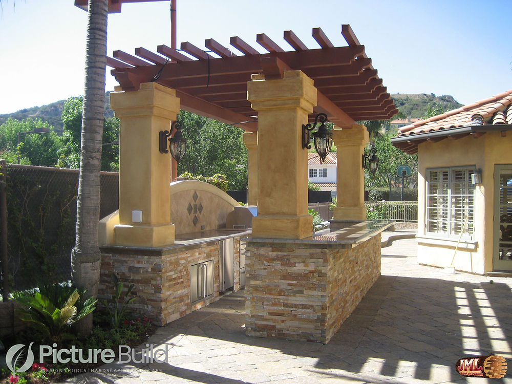 Covered stone outdoor kitchen featuring stone walls and columns.