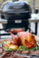 A amber colored turkey with a Primo Grill in the back.