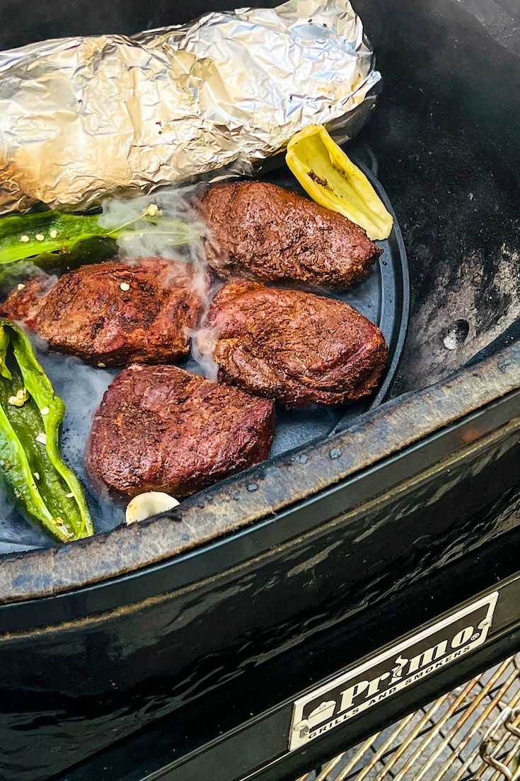 Four smoked top sirloin are on a cast iron griddle and will be charred on both sides.