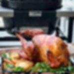 A beautiful amber turkey is done cooking. It is on a platter with golden onions.