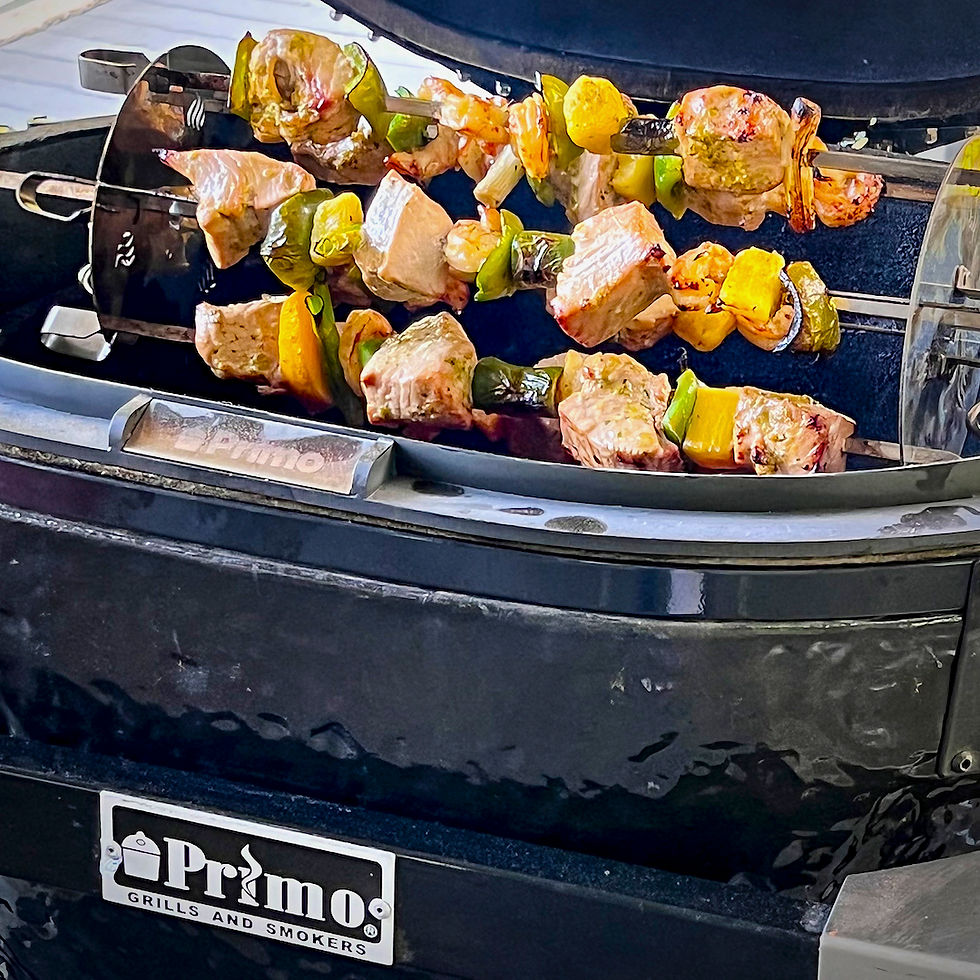 A closer look at sea bass, peaches, and peppers on a rotisserie skewers.