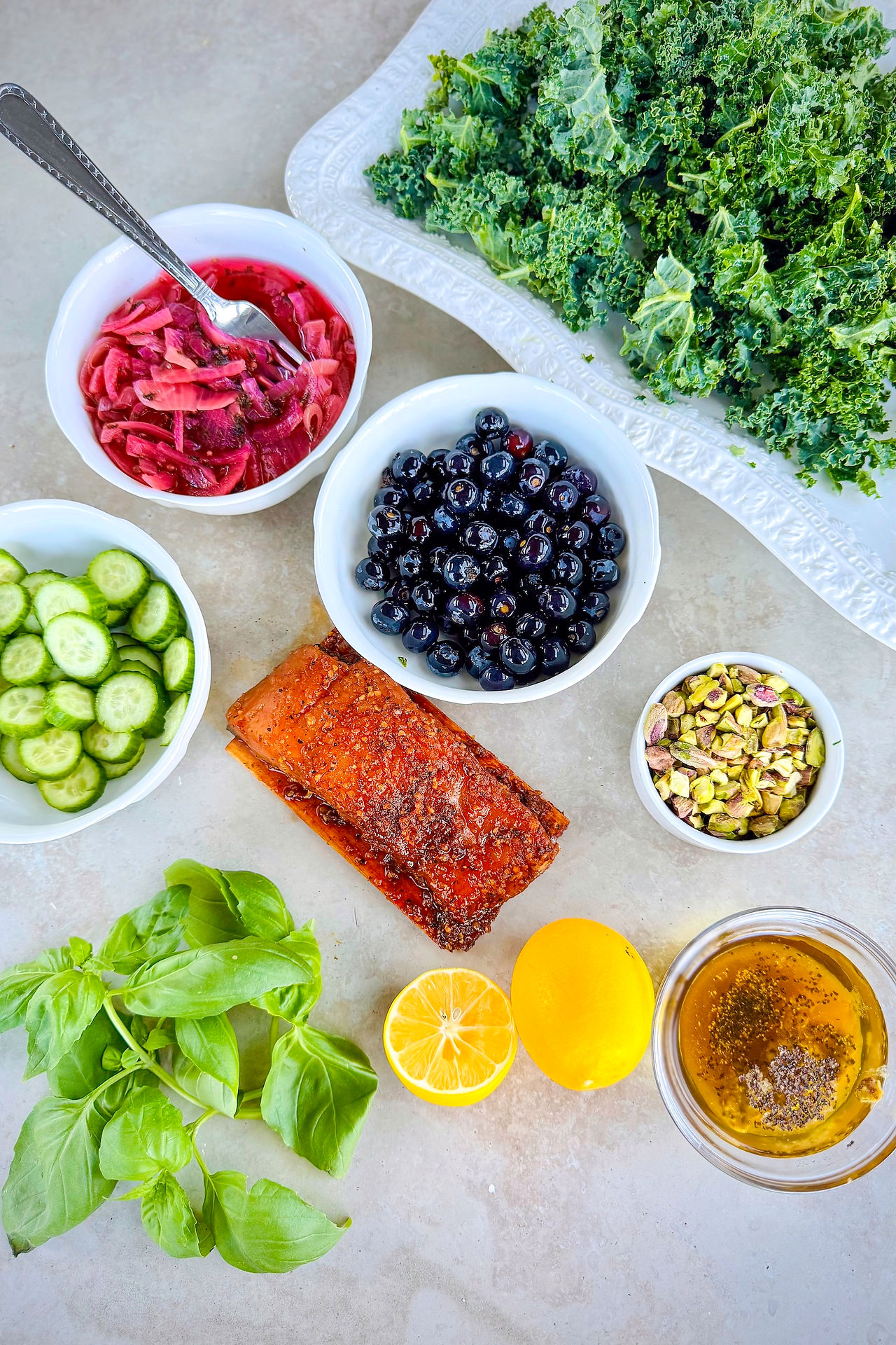 Lemons, blueberries, basil, Salmon, and pistachios are ready to be tossed into a salad. 