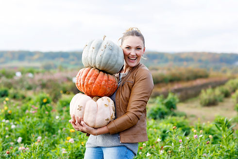 Beautiful young woman with three huge different pumpkins on a farm or patch. Girl having f
