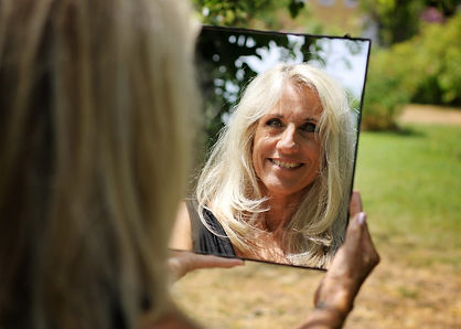 Man sieht Ilonka´s Hinterkopf und ihr Gesicht in einem Spiegel, den sie vor sich hält