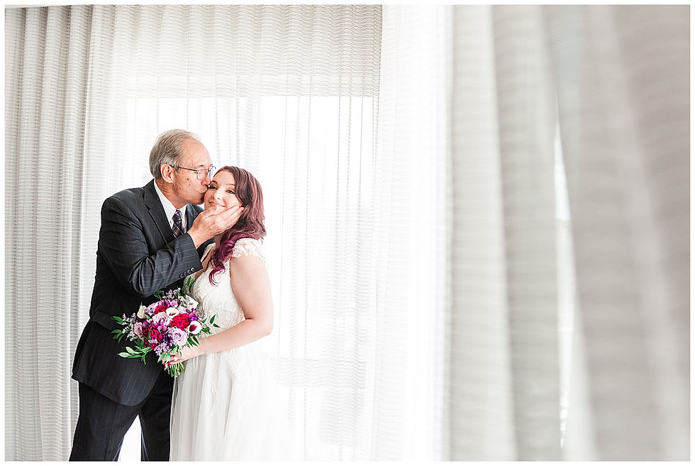 Dad kissing bride on the cheek by the window of hotel suite Andalusia PA wedding