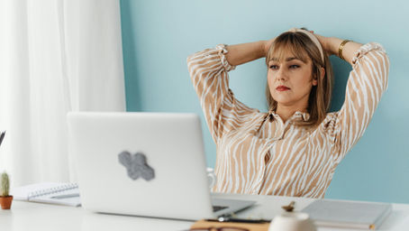 Eine nachdenkliche Frau sitzt vor einem Laptop und blickt nach oben – Symbolbild für Unsicherheit oder Recherche, etwa im Zusammenhang mit einem SCHUFA-Eintrag oder rechtlichen Fragen