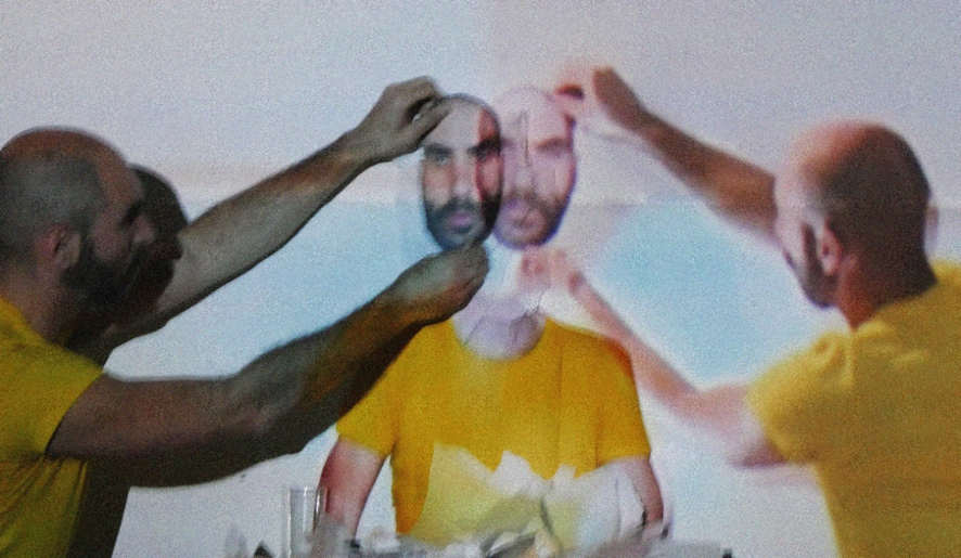 Cena da obra “¿Cómo as coisas chegaram aquí”, de Iván Haidar, com performer de camiseta amarela diante de projeções sobrepostas e gestos corporais em composição visual experimental.