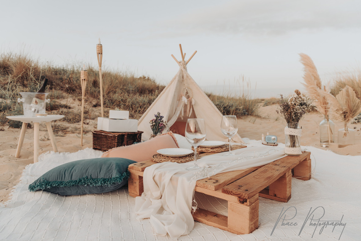Picnic table setting with glasses and cushions by the dunes