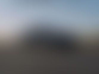 Das neue Bentley Modell "Continental GTC S." steht auf einer dunkelgrauen feinen Schotterfläche. im Hintergrund sieht man ein paar Steine und eine Wiese mit verschiedenen Pflanzen und am Horizont etwas das Meer