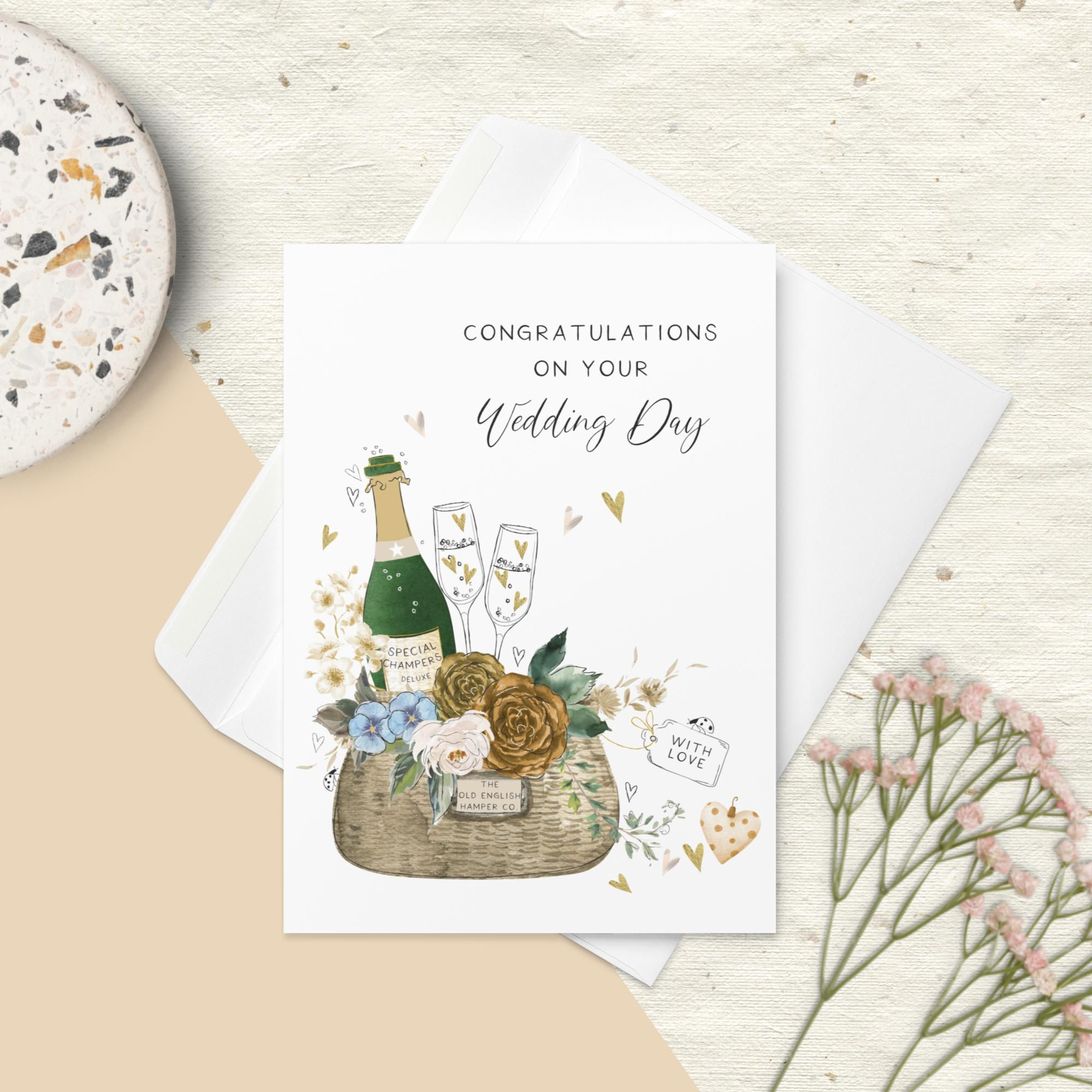 "CONGRATULATIONS on your Wedding Day" card with a celebratory champagne bottle, flutes, a wicker basket with flowers.