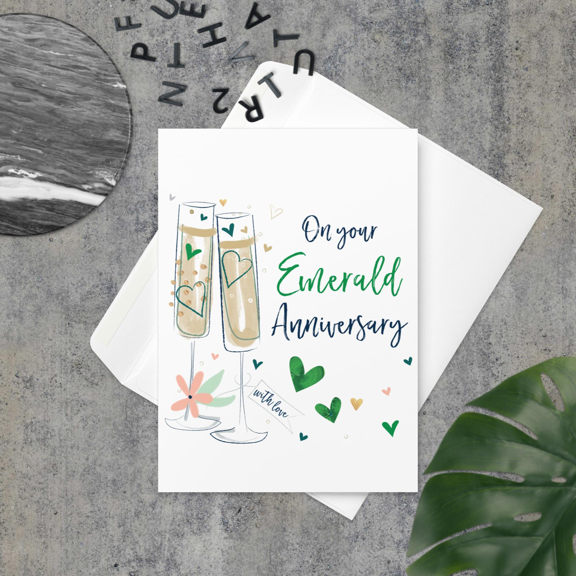 Emerald Anniversary greeting card with champagne glasses and green heart decorations.