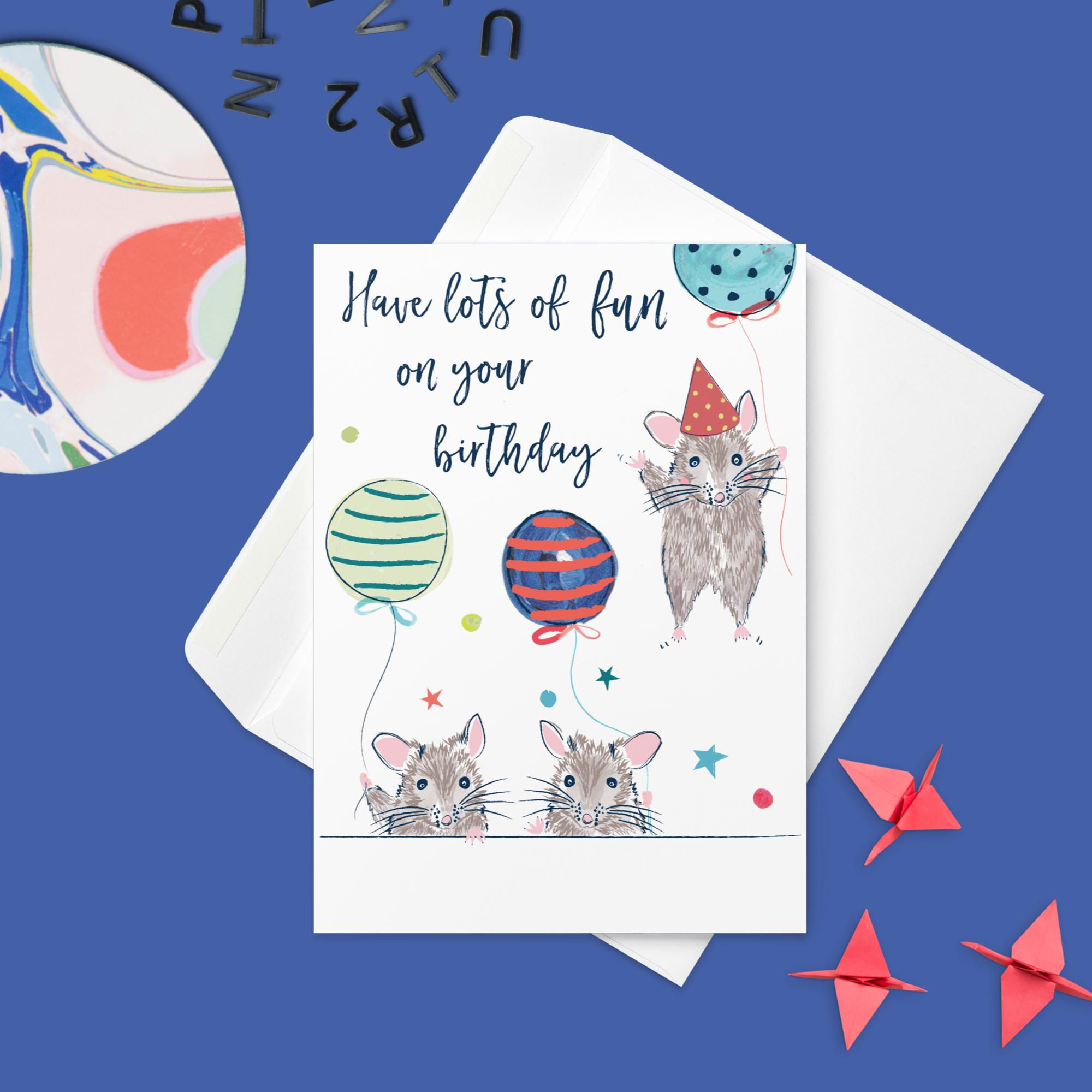 birthday card displayed at an angle, featuring an illustration of three adorable mice in party hats.