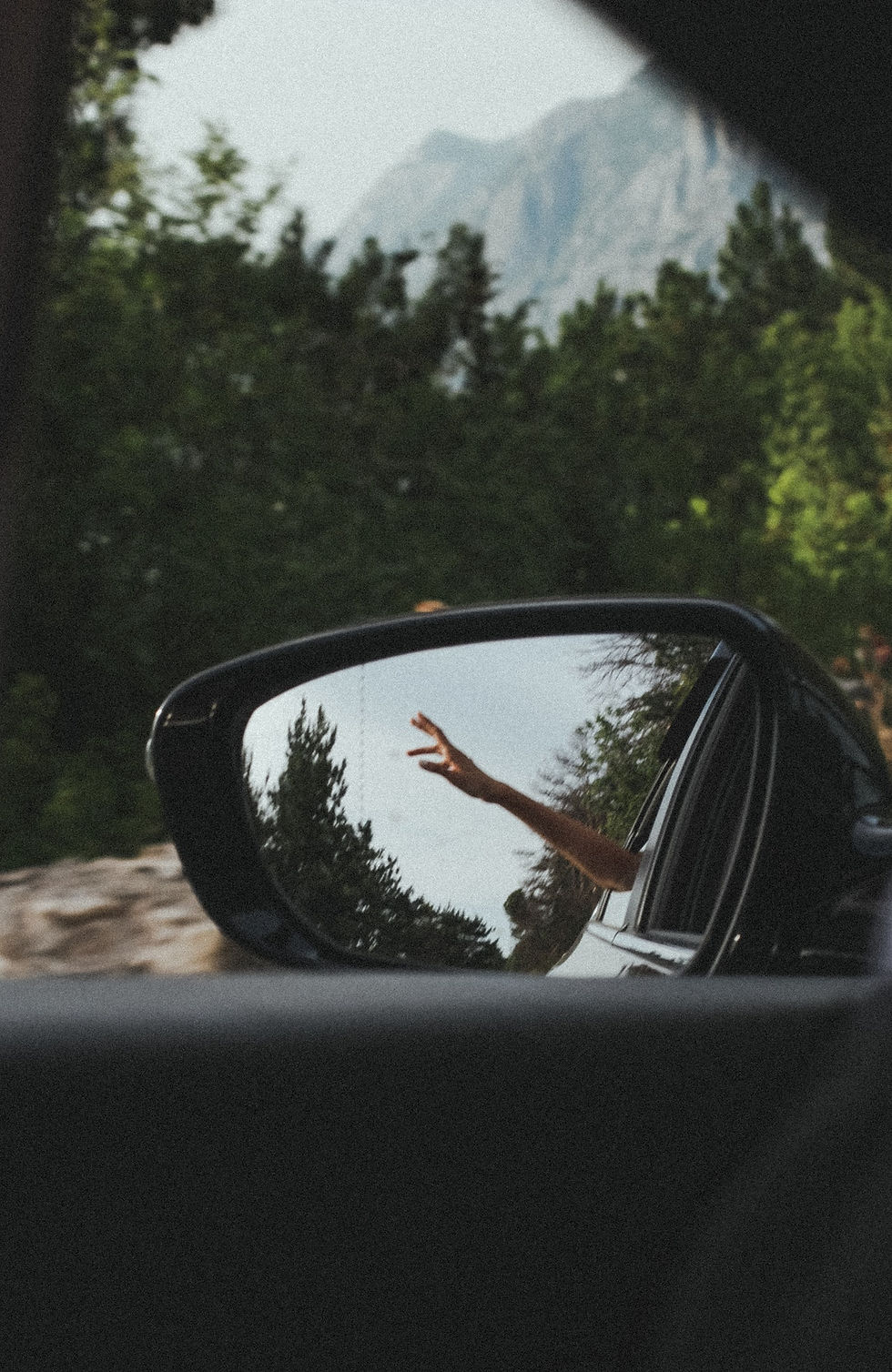 Photo d'un rétroviseur de voiture dans lequel on voit une main sortir de la fenêtre du véhicule