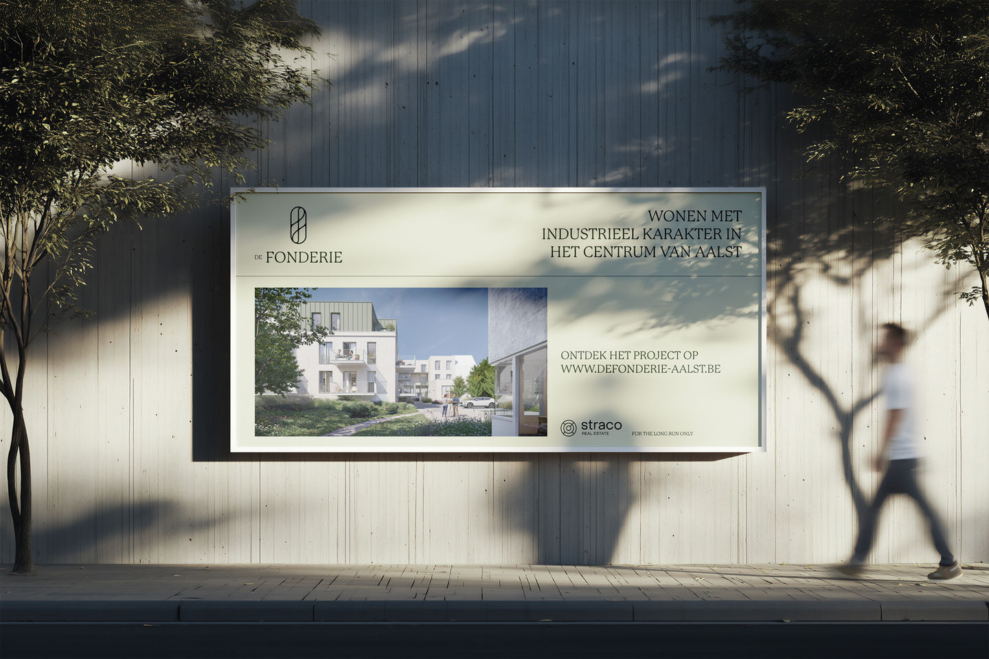 Advertentie voor een vastgoedproject op een billboard, bevestigd op een betonnen muur met de schaduw van bomen die er op valt.
