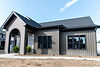 Modern ranch home with dark vertical siding and a stone entryway porch.