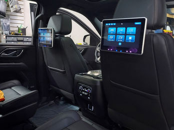 Car interior with two screens attached to the headrests, showing menu.