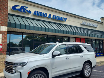 White SUV parked in front of C & R Audio & Security store.