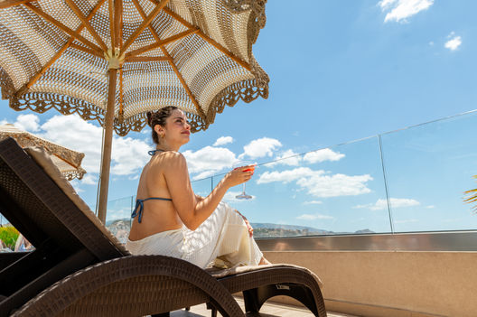 Γυναίκα με κοκτέιλ σε ξαπλώστρα στο Green Suite Hotel.