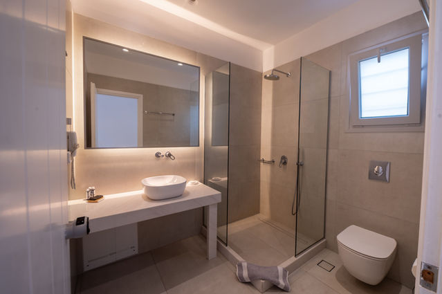Μοντέρνο μπάνιο με ντους και καθρέφτη στο The George Hotel Mykonos.