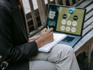Professional planning a content strategy with a laptop, notebook, and digital content research.