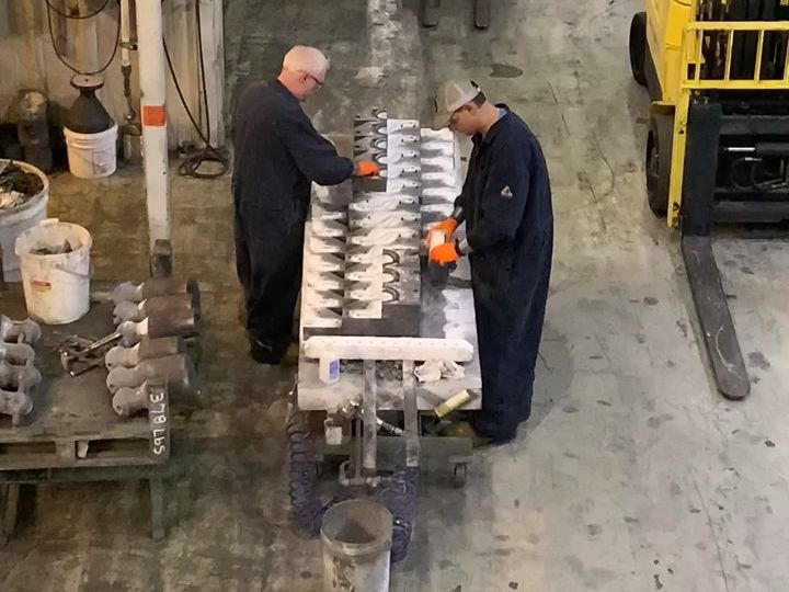 Two MSC employees sorting finished castings at a table in the Oak Ridge foundry