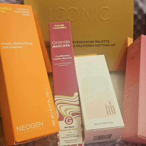 A flat lay of beauty products from the August 2025 IPSY BoxyCharm, including skincare, mascara, setting spray, and an eyeshadow palette.