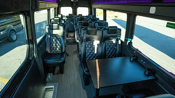 Luxury Mercedes Sprinter interior with leather captain's chairs, table, and TV for private Banff tours