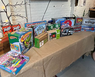 A table full of toys and games is shown in the photo, all of which were donated to NH Toy.