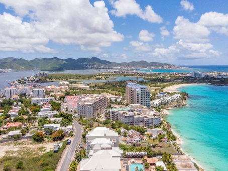 Drone view of Cupecoy, Sint Maarten, featuring crystal-clear Caribbean waters, beachfront resorts, luxury vacation rentals, and panoramic island scenery.