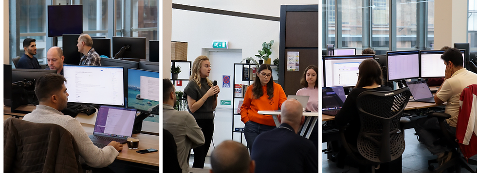 Kantoor met medewerkers aan computers; in het midden geeft een vrouw in oranje een presentatie voor collega’s.