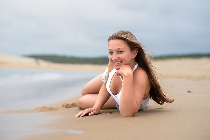 Jeune fille souriante assise sur la plage, séance portrait dans les Landes