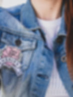 A woman wearing a heaven patch on a denim jacket