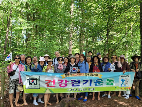 "건강걷기운동" 현수막을 들고 숲에서 찍은 함부르크 한인회 단체사진 (Hamburg Korean Association members holding the "Health Walking" banner in the forest at Barfußpark Egestorf)
