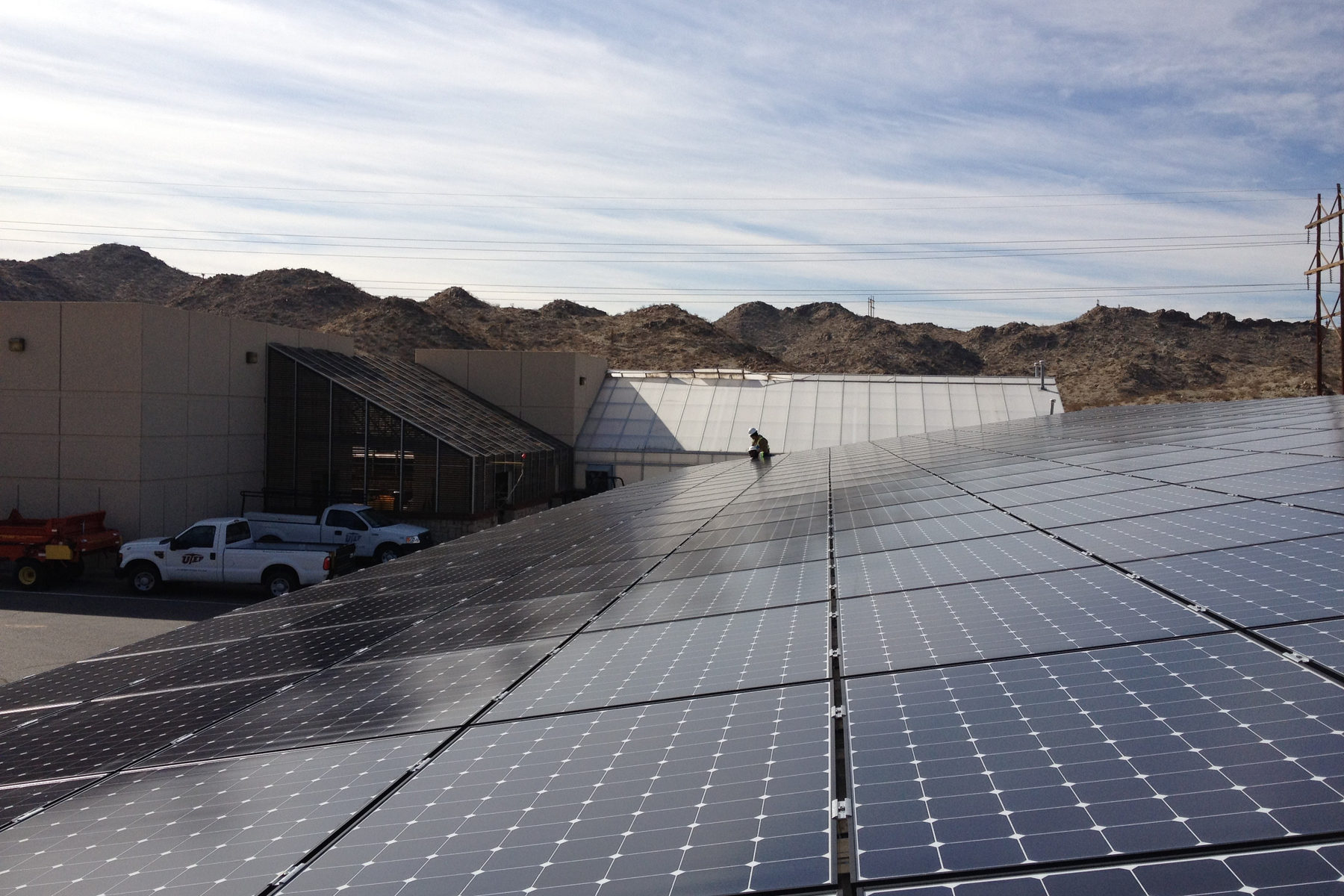 UTEP's first solar installation on campus: a 185 kW system combining a rooftop array on the Student Recreation Center with a parking canopy at the Facilities Services Building, funded by a $1M SECO grant and the UTEP Green Fund.