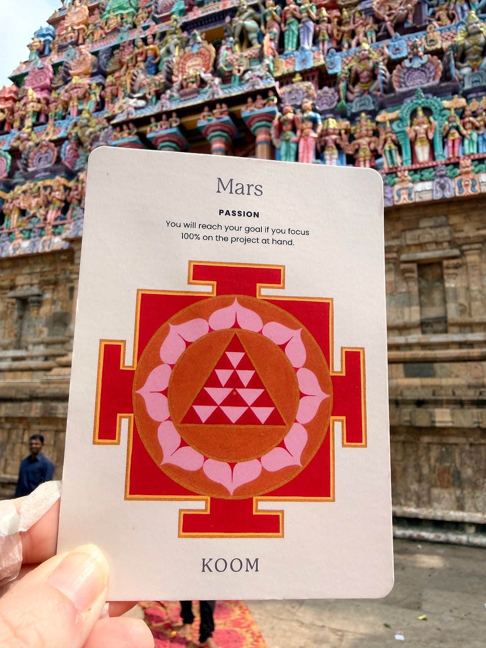 Card with "Mars" text and red geometric design held in front of colorful temple, detailed carvings in background. Positive motivational text.