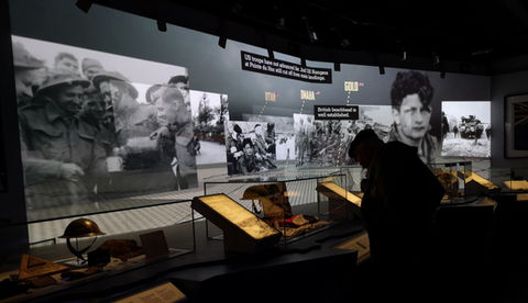 Long metres of projected film on a wall wrap around a viewer - showing AY-PEs CGI motion edit archive film of the colossal scale of D-Day landings, at The D-Day Story.