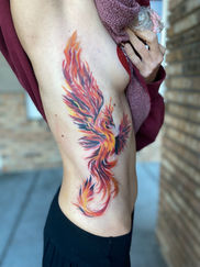 Colorful phoenix tattoo art on a person's side, metamorphosis; colorful Pheonix tattoo; rib tattoo; Ciara Meyer Tattoos; tattoo; metamorphosis ink; Dunedin; Dunedin florida; Dunedin causeway; florida; florida tattoo artist; tattoo shop near me; color; color tattoo artist; realism artist; fine line tattoo artist; female tattoo artist; best female artist; tattoo artist of florida; paramedical tattoo artist; breast cancer tattoo artist; mastectomy tattoo artist; scar cover up artist; 