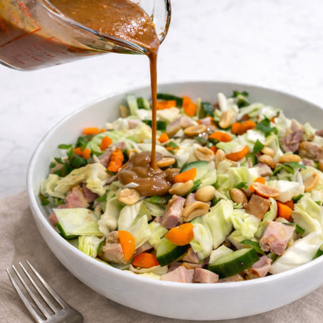 Creamy Asian peanut dressing drizzled over cabbage salad with chicken and peanuts